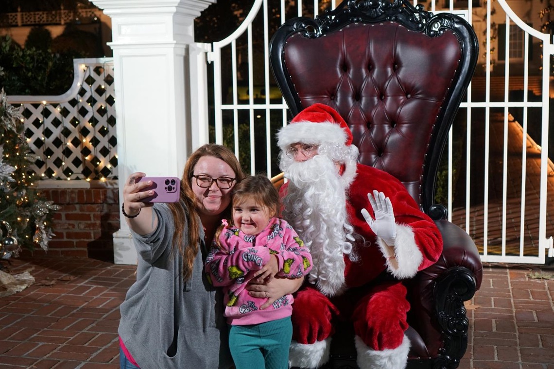 Santa poses for photo with child and woman