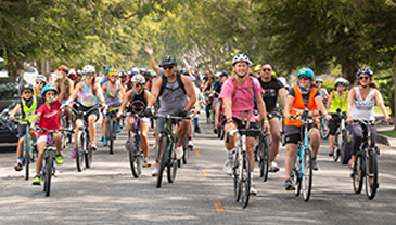 Bikers off all ages riding down a street