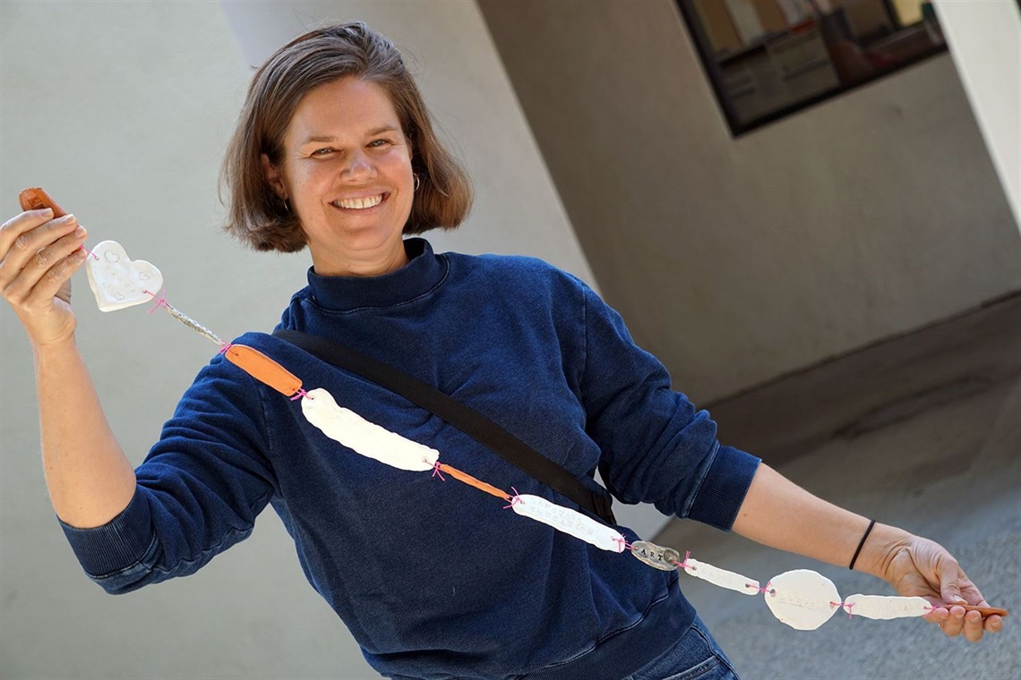 Photo of Artist Laureate Katy Krantz holding a string of ceramic art pieces