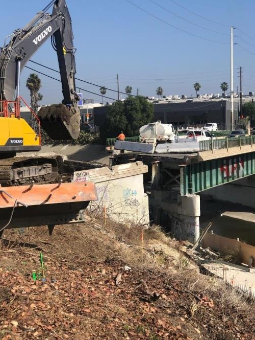 Photograph of demolition of Higuera Street Bridge, showing construction equipment working to remove a segment of bridge